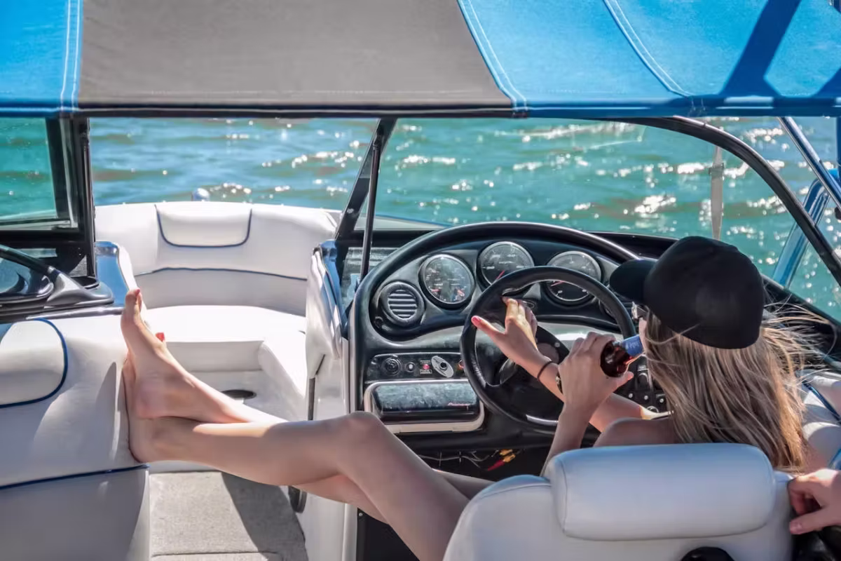 A woman is driving a boat, showcasing her skill and confidence in navigating the water.